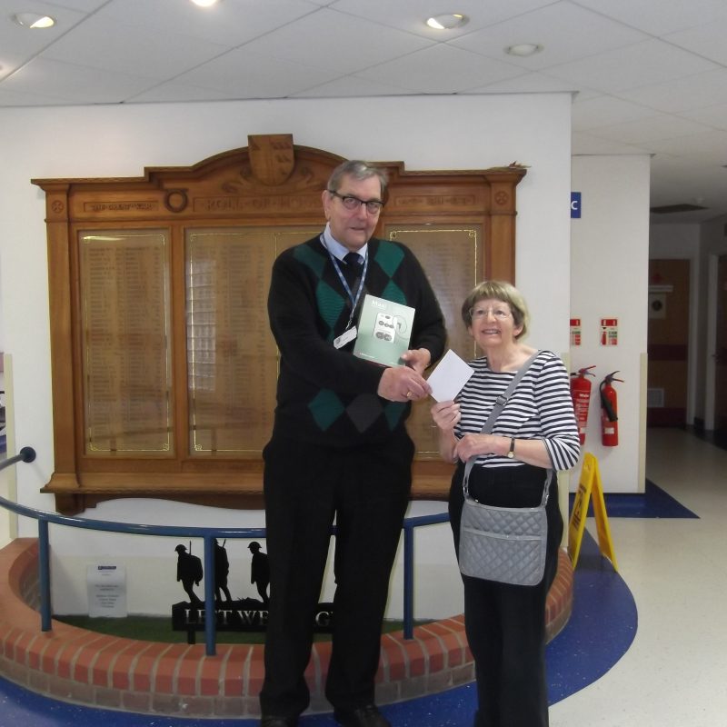 Chairman and SVP representative standing in front of the War Memorial, receiving the hearing amplifier.