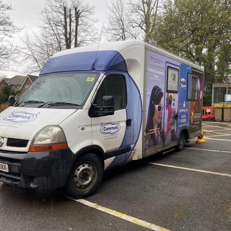 Medium sized Dementia Bus with colourful livery parked in the car park of the hospital
