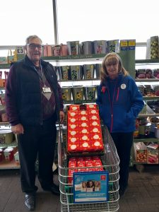 Chairman Brian Knight and Jackie from Tesco stand at the store, either side of a shopping trolley filled with 48 Easter Eggs in red boxes