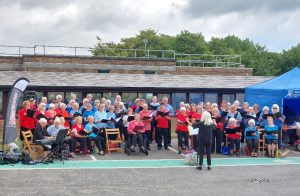 Felpham Community Choir sing together, wearing red, royal blue and light blue tshirts