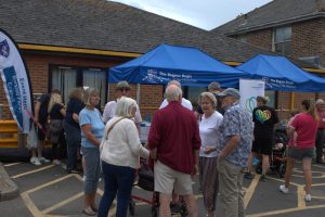 Attendees chat happily in front of two Friends liveried covered stalls in the hospital grounds