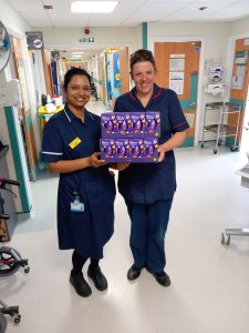 Two staff members holding purple Easter Eggs for the wards